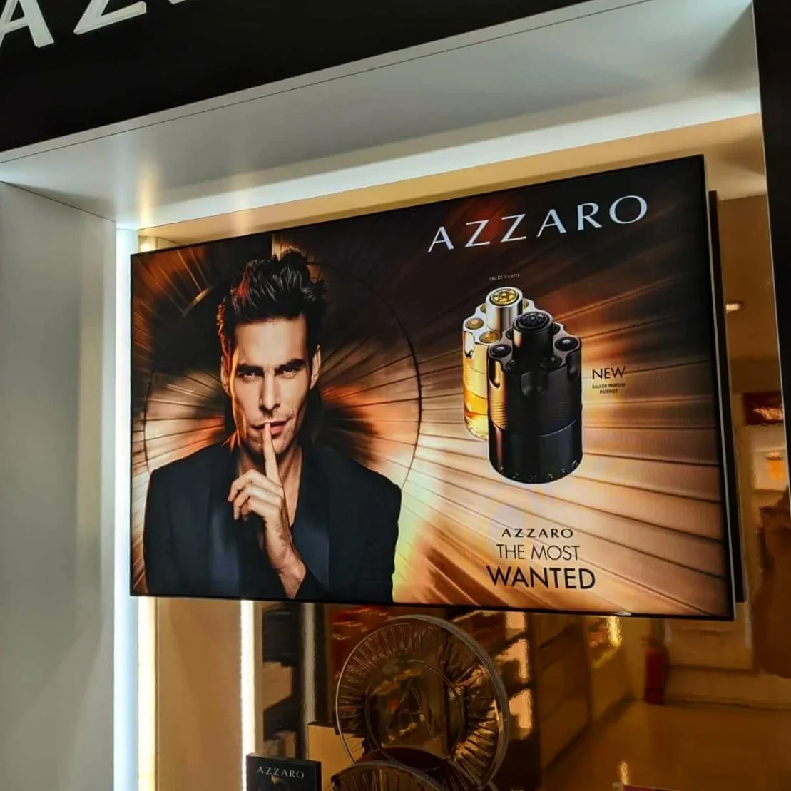 Podświetlany kaseton reklamowy perfum marki premium zawieszony w witrynie sklepowej