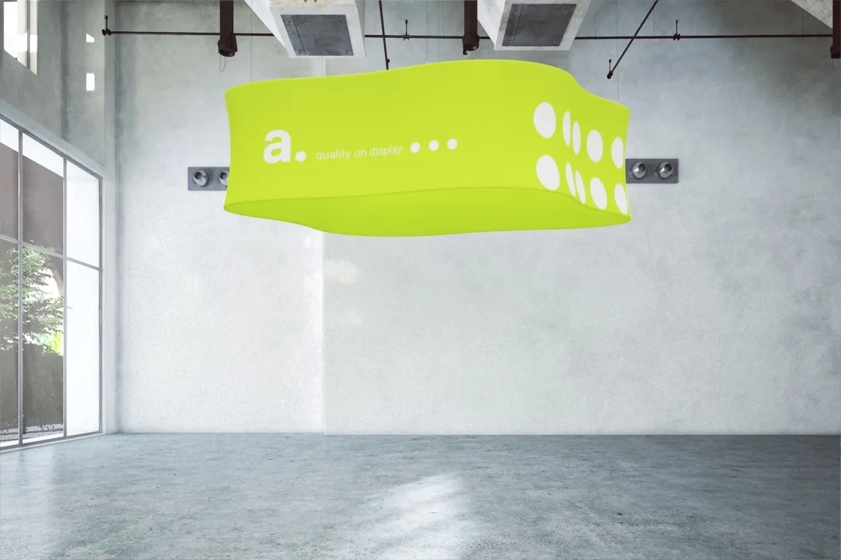 Podwieszany system tekstylny o faliście wygiętej formie, zawieszony w nowoczesnym, industrialnym wnętrzu – przykład kreatywnej aranżacji przestrzeni wystawienniczej.