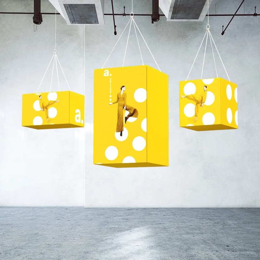 Trzy przestrzenne ramy tekstylne, podwieszone pod sufitem w nowoczesnej, pustej hali.