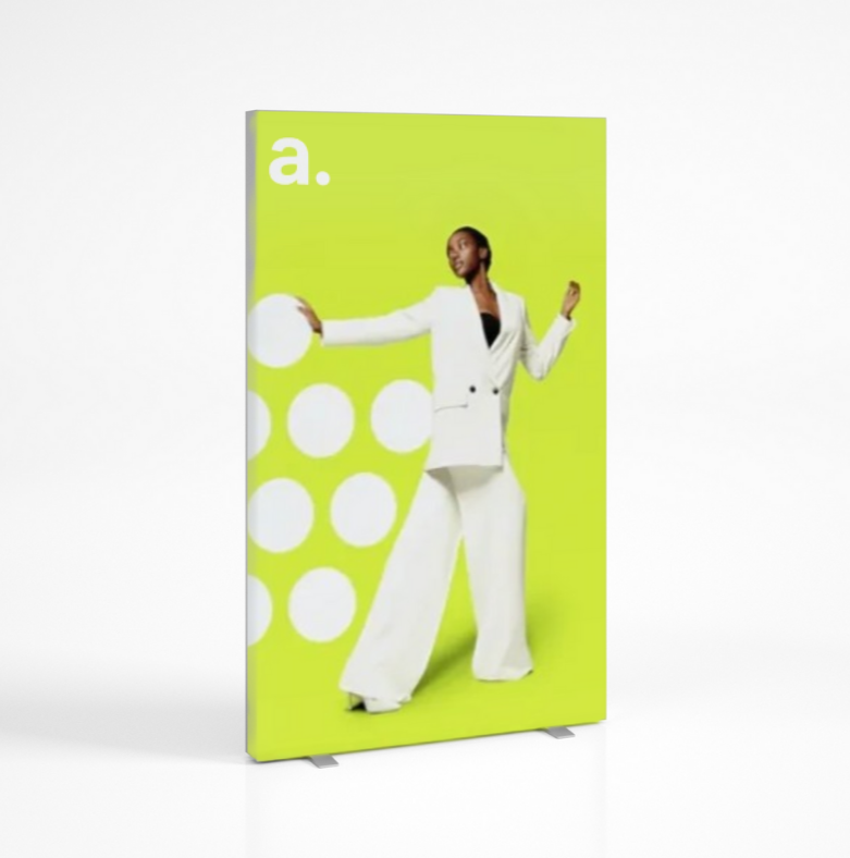 Wolnostojący kaseton tekstylny z grafiką reklamową – model adFrame LMD na tle białym, z intensywnie żółto-zieloną grafiką i postacią kobiety w białym garniturze.