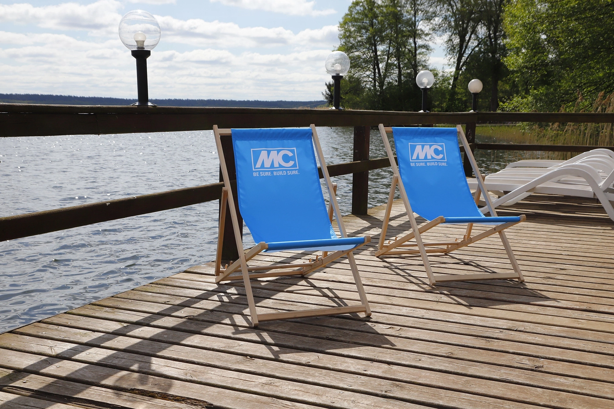 Leżaki reklamowe z logo na pomoście na tle jeziora