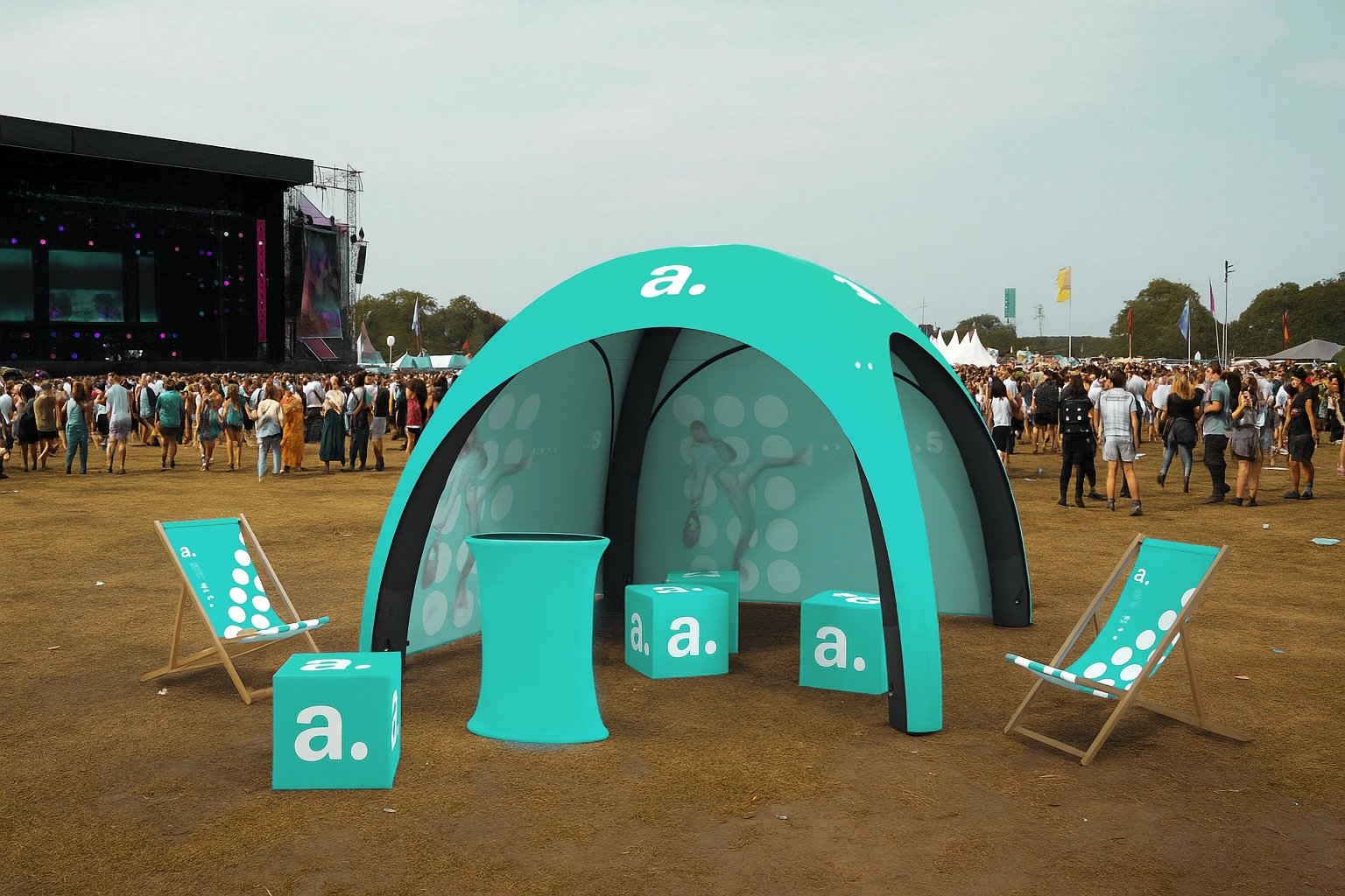 Strefa eventowa z namiotem reklamowym, leżakami i pufami z logo „a.” na tle festiwalu muzycznego.