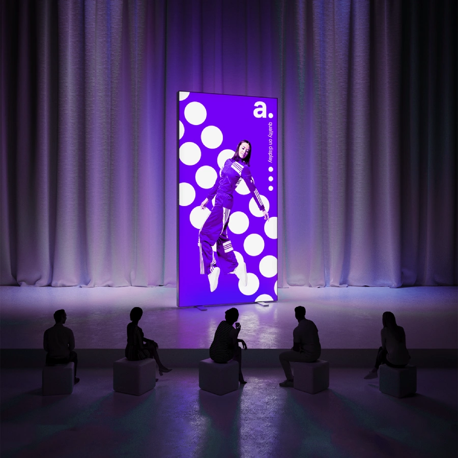 Podświetlany kaseton LED z grafiką, prezentowany przed publicznością w ciemnej sali z zasłonami.