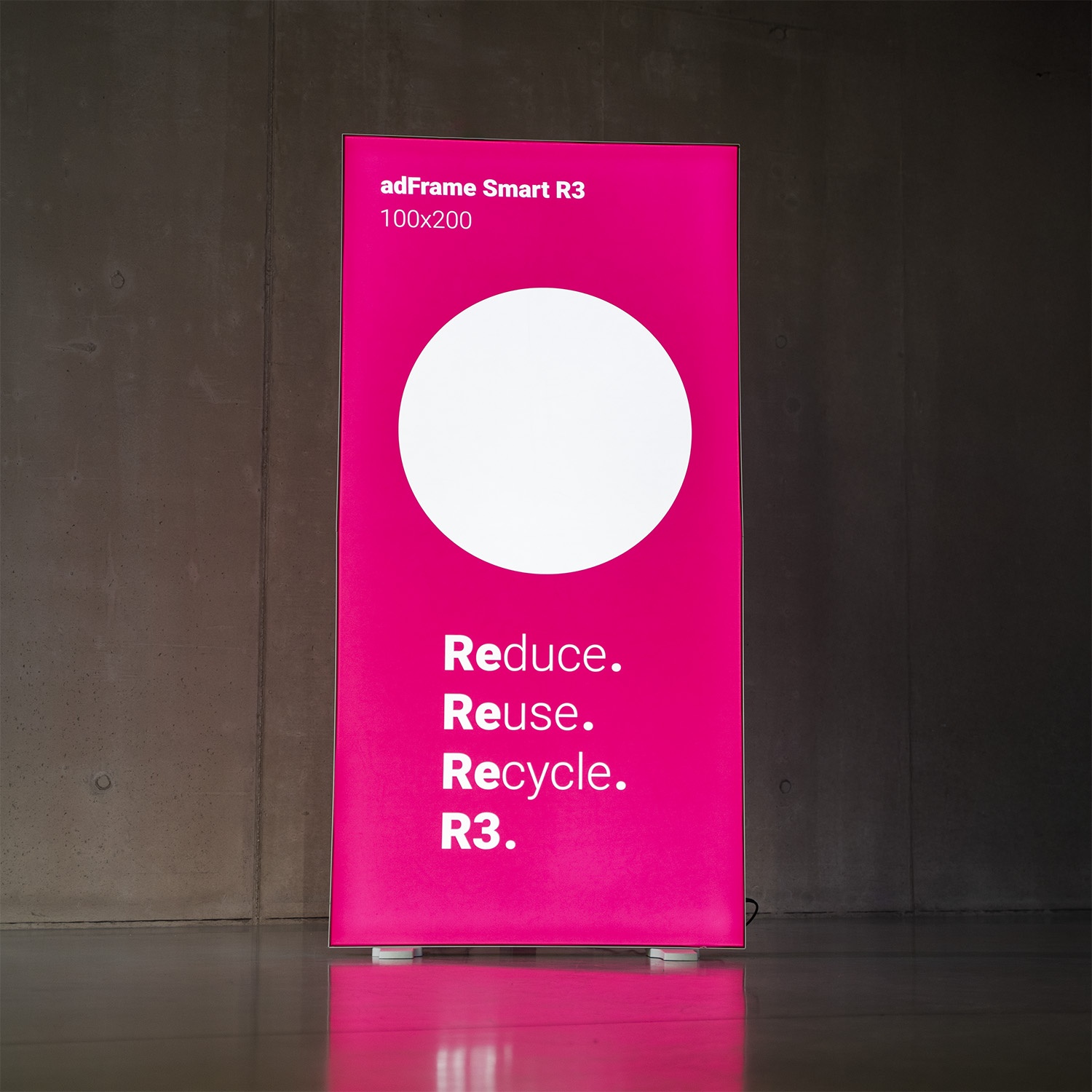 Podświetlany kaseton adFrame Smart R3 z wymienną grafiką w systemie SEG, prezentujący hasło „Reduce. Reuse. Recycle.” jako przykład materiału wielokrotnego użytku.