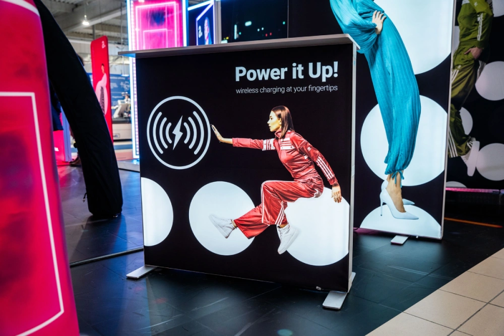 Mostrador publicitario retroiluminado con cargador inalámbrico integrado, diseñado para stands interactivos en ferias y eventos.