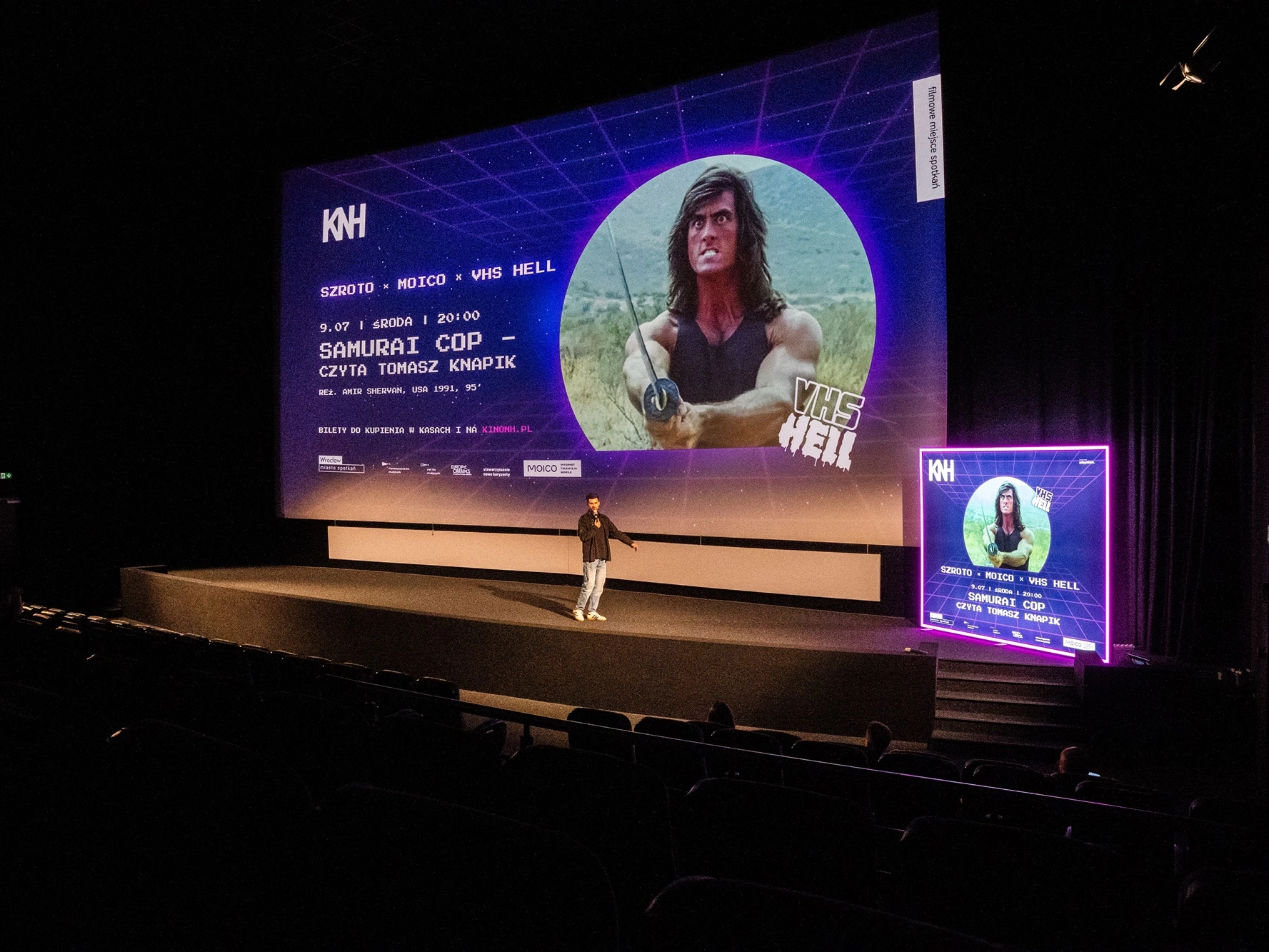 file-meta-description.zdjęcieprzedstawiasalękinowąpodczaswydarzeniapromującegofilm-samurai-cop,zdużymekranemipodświetlanymkasetonemreklamowymustawionymoboksceny.