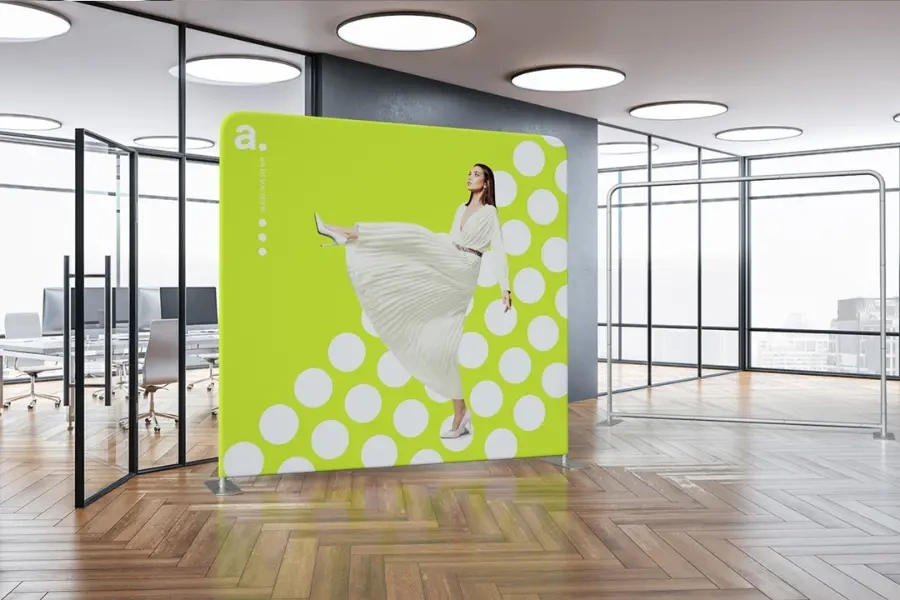 Photocall publicitario colocado en una oficina moderna, con diseño colorido y figura de una mujer, ideal para decorar espacios y hacer fotos durante eventos corporativos.