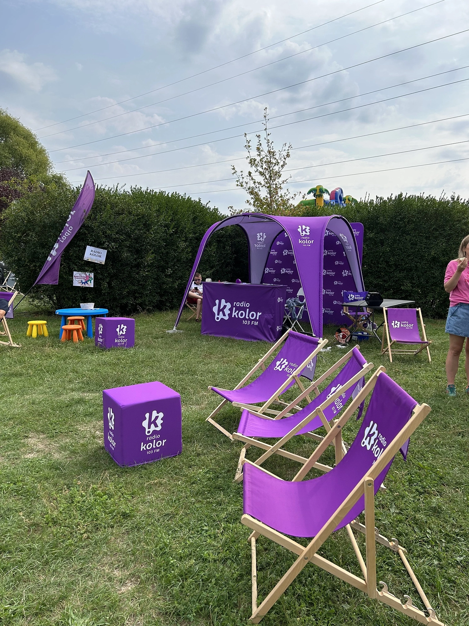 Namiot reklamowy, leżaki i pufy reklamowe, ustawione w ogrodzie podczas wydarzenia plenerowego