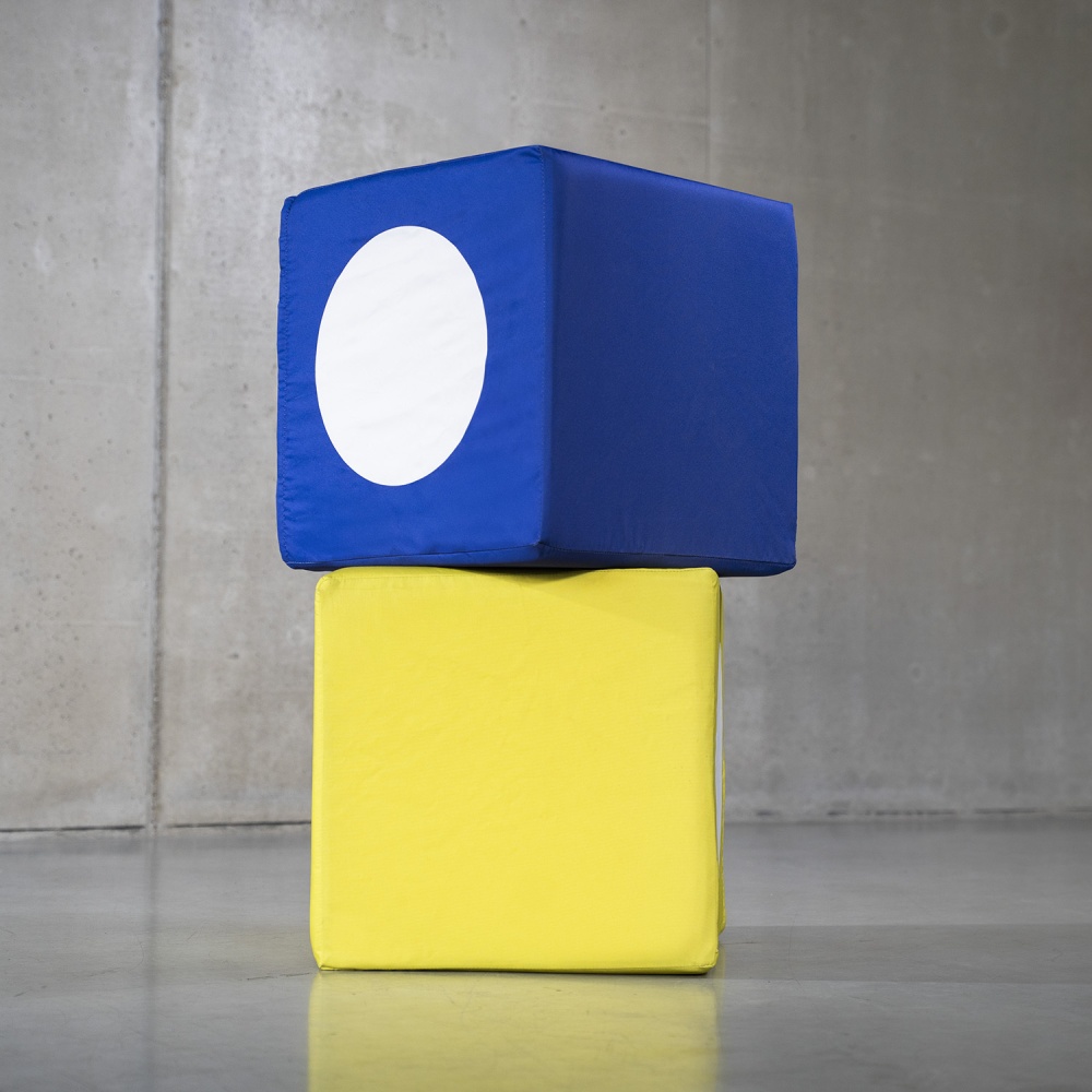 Dwa miękkie pufy kostki z wymiennymi pokrowcami prezentujące możliwość ponownego wykorzystania grafik.