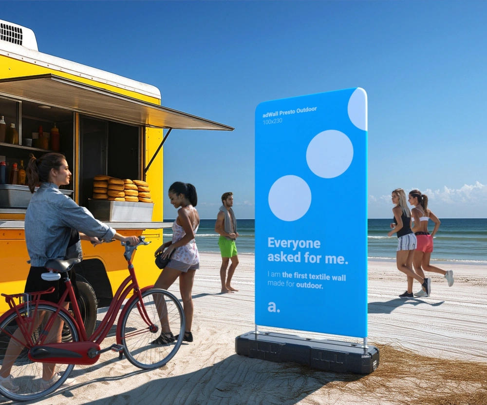 Ścianka reklamowa zewnętrzna z tekstylnym wydrukiem, prezentowana na plaży obok food trucka.