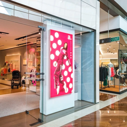 Caisson lumineux LED avec publicité mode à l’entrée d’un magasin dans une galerie commerciale moderne, avec intérieur et présentation produits visibles