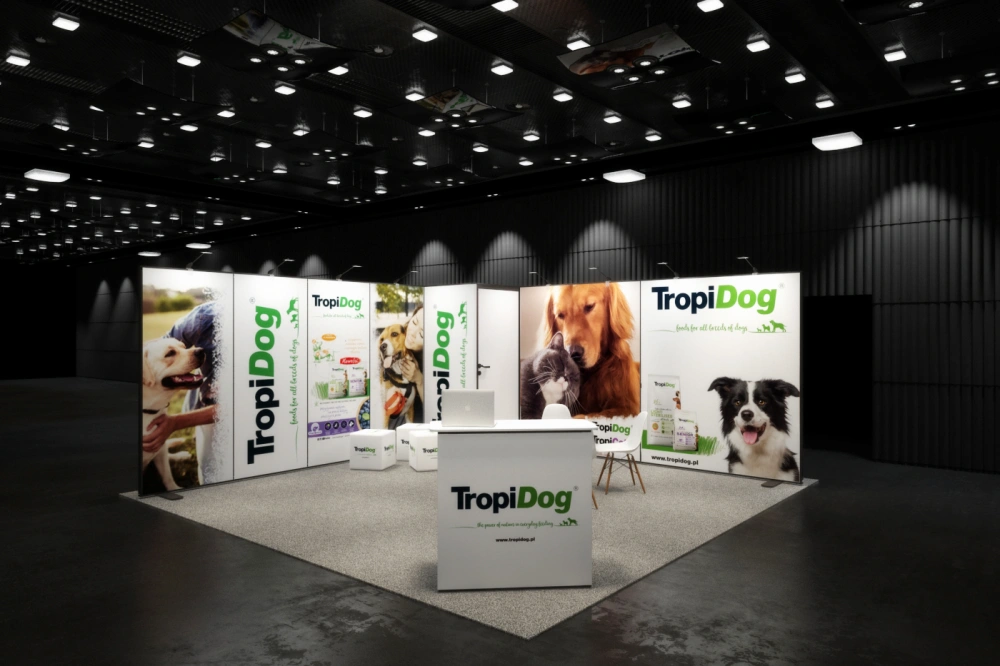 Stoisko targowe TropiDog z dużymi grafikami przedstawiającymi psy i kota, białą ladą z logotypem oraz strefą rozmów wyposażoną w krzesła i pufy reklamowe.