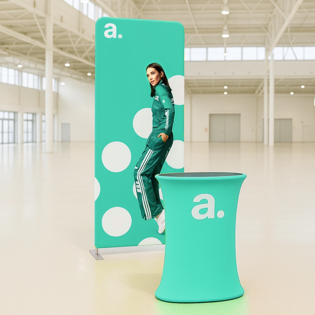 Set promocional compuesto por un photocall textil y un mostrador en color menta con logo blanco “La.”, colocado en un espacio ferial