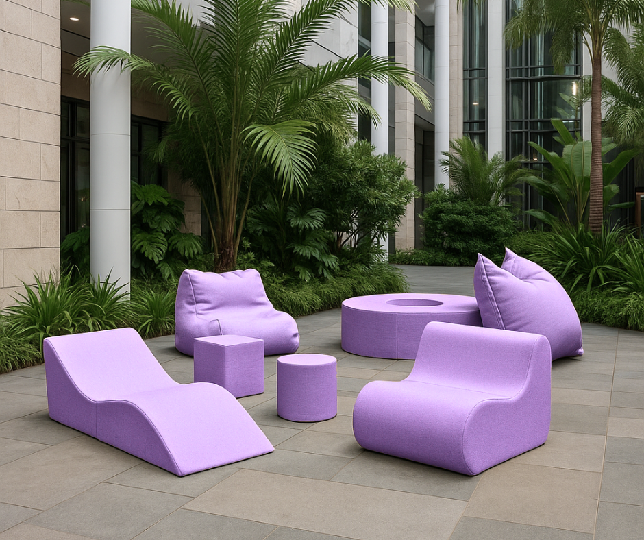 Nowoczesne meble wypoczynkowe w kolorze fioletowym ustawione w zielonym, tropikalnym atrium biurowca – przestrzeń do relaksu lub spotkań w stylu lounge.