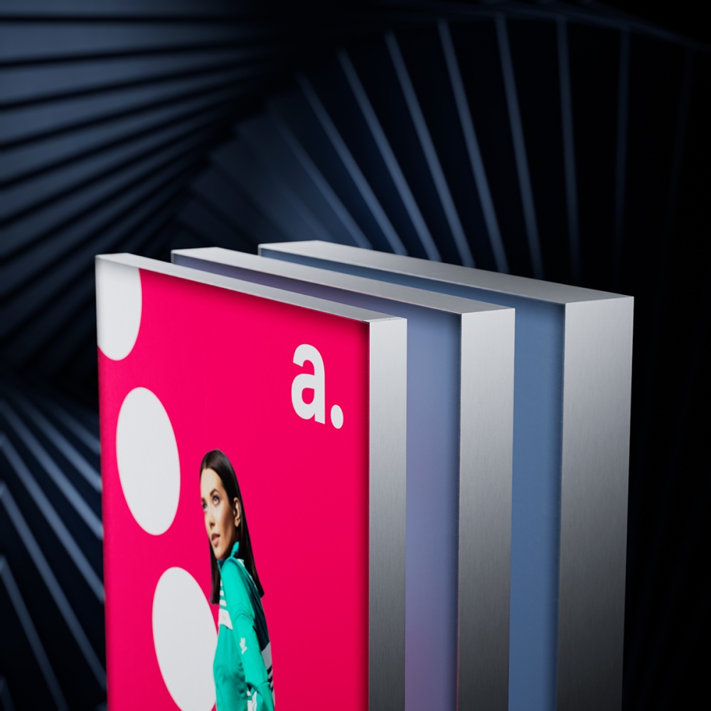 Zbliżenie na kasetony reklamowe z profilu Slim, prezentujące aluminiową ramę i naciągniętą grafikę tekstylną w intensywnych kolorach, na tle nowoczesnego wnętrza.