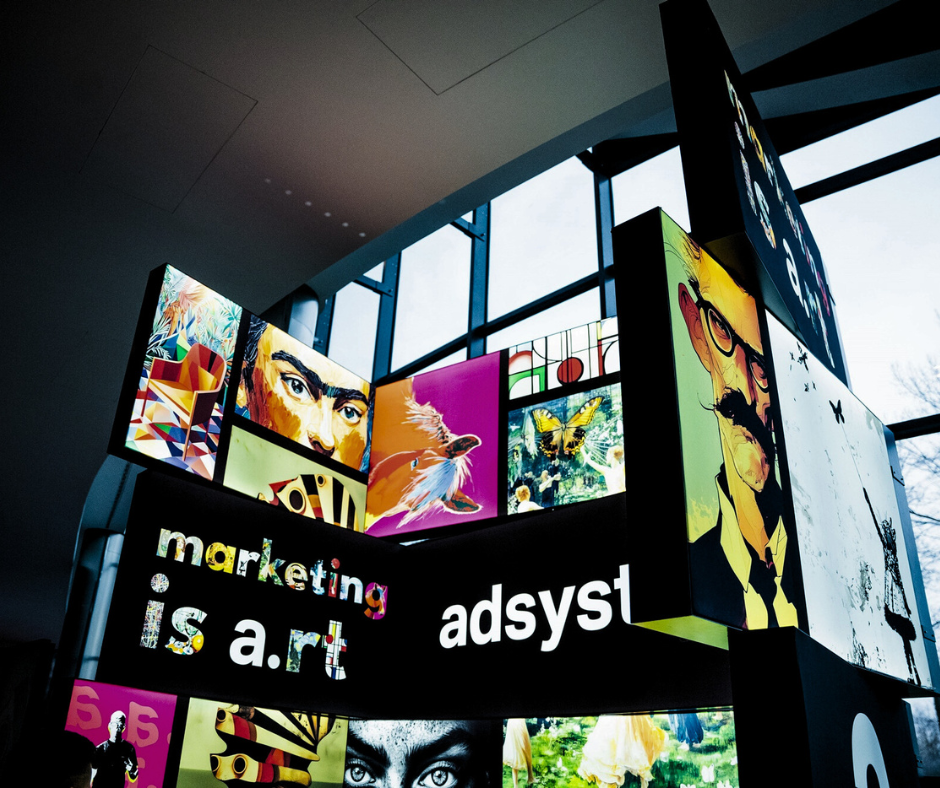 Instalacja z podświetlanych kasetonów reklamowych z grafikami artystycznymi i hasłem „marketing is art”, w nowoczesnym, przeszklonym wnętrzu.