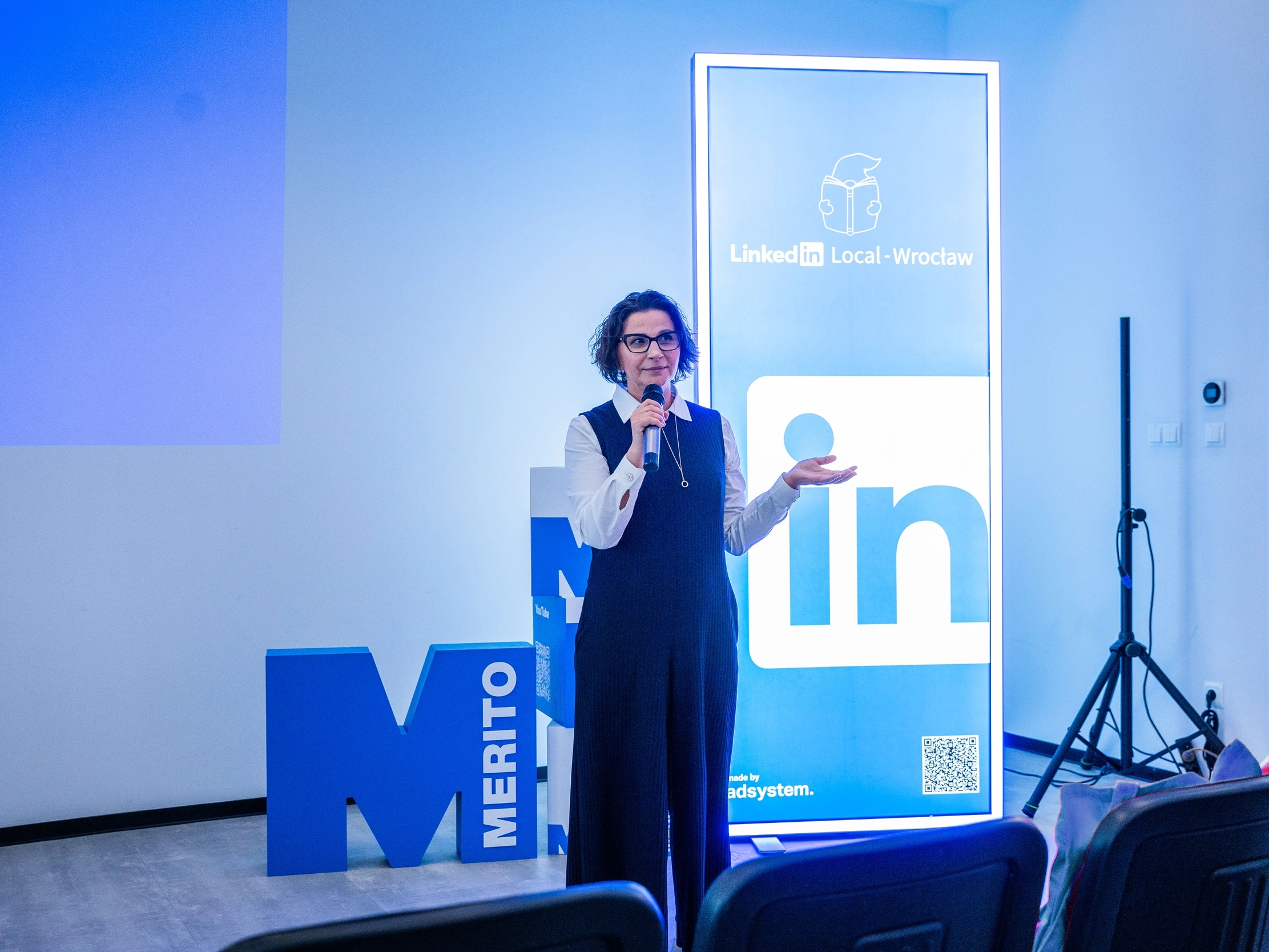 Panneaux lumineux LinkedIn Local Wrocław servant de décor pendant qu’une intervenante s’exprime devant le public.