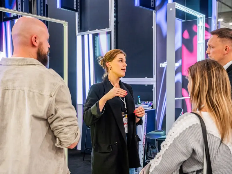 Kobieta prezentuje elementy zabudowy targowej grupie uczestników wydarzenia.