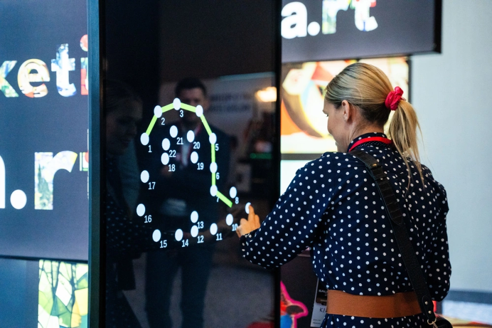 Pantalla interactiva adsystem en feria, diseñada para atraer la atención y generar interacción mediante juegos y contenidos digitales.