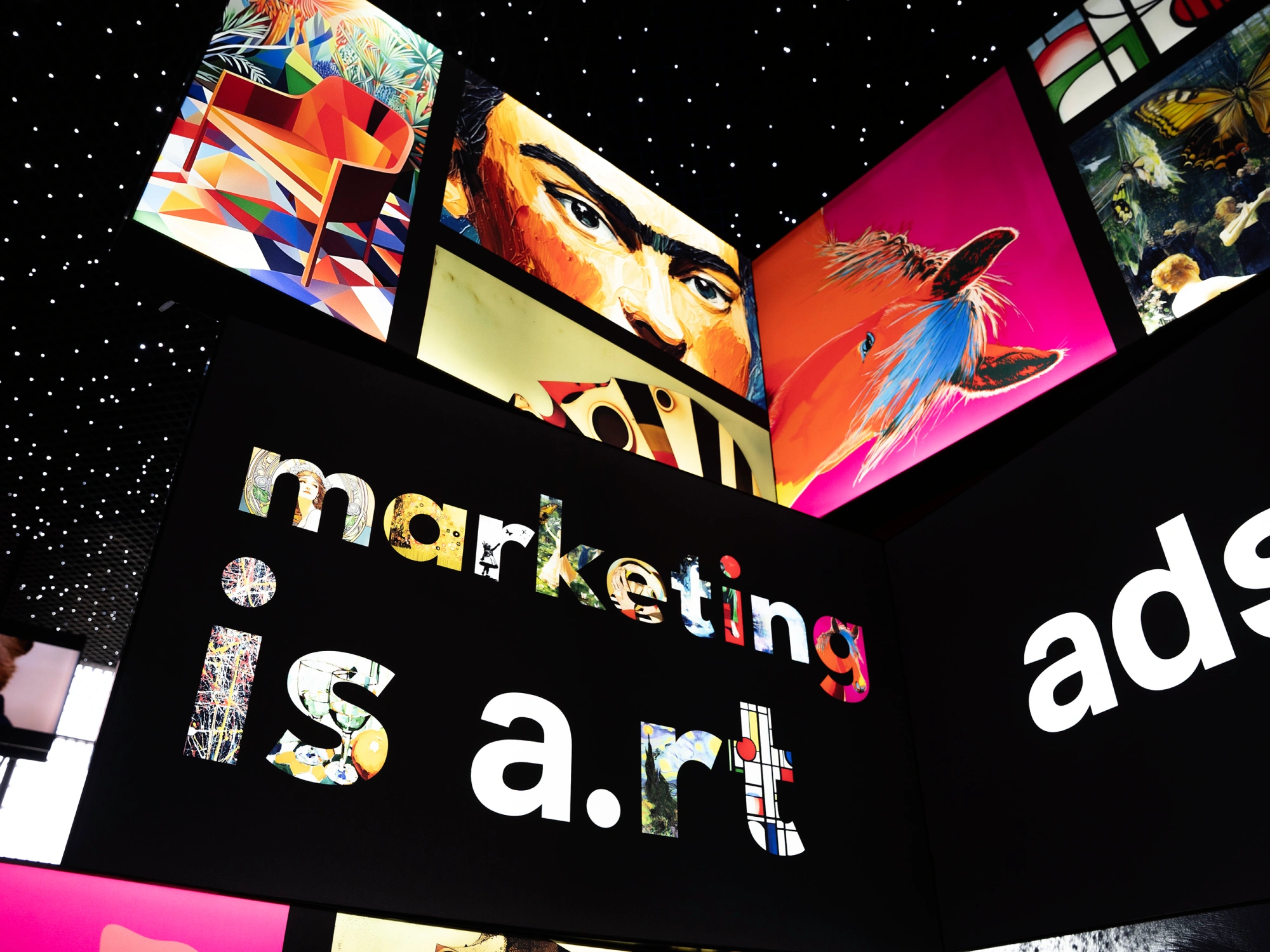 Panneaux lumineux artistiques affichant des visuels colorés et le slogan « marketing is art » dans un espace d’exposition.