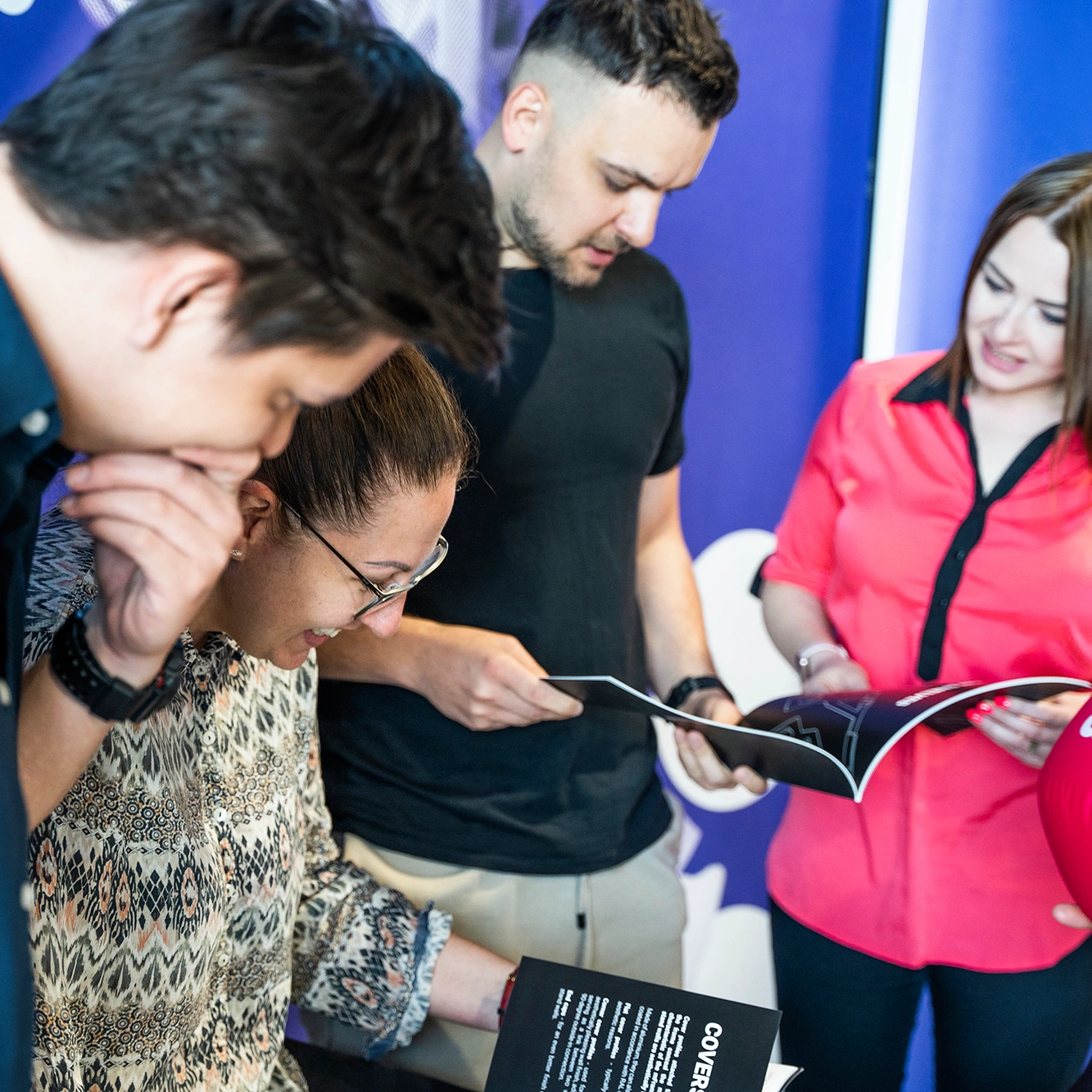 Grupa osób ogląda wspólnie materiały drukowane podczas spotkania lub prezentacji.