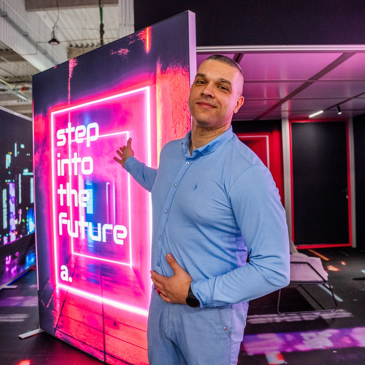 Osoba prezentująca kaseton reklamowy adsystem z neonową grafiką i napisem „step into the future” na stoisku targowym.