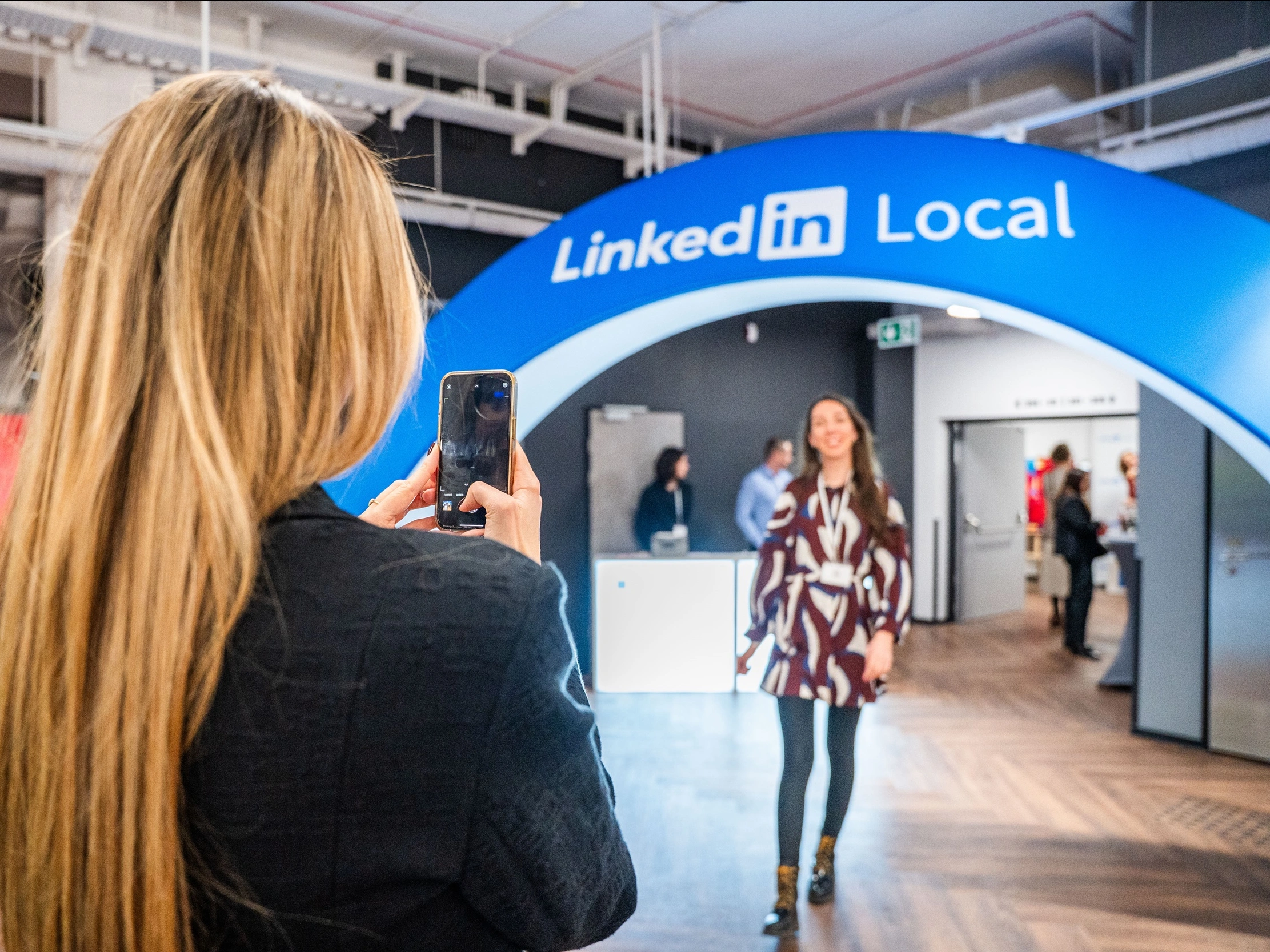 Participant prenant en photo une personne passant sous une arche LinkedIn Local lors de l’événement.
