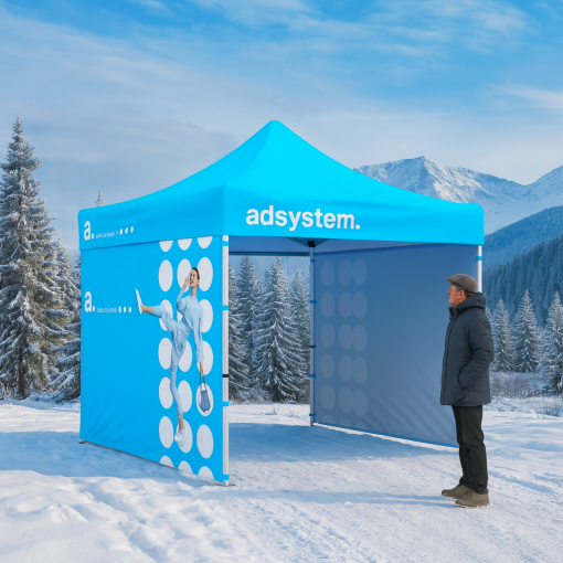 Tente publicitaire adsystem installée dans un paysage montagnard hivernal, entourée de neige et d’arbres enneigés, avec un homme à côté de la structure