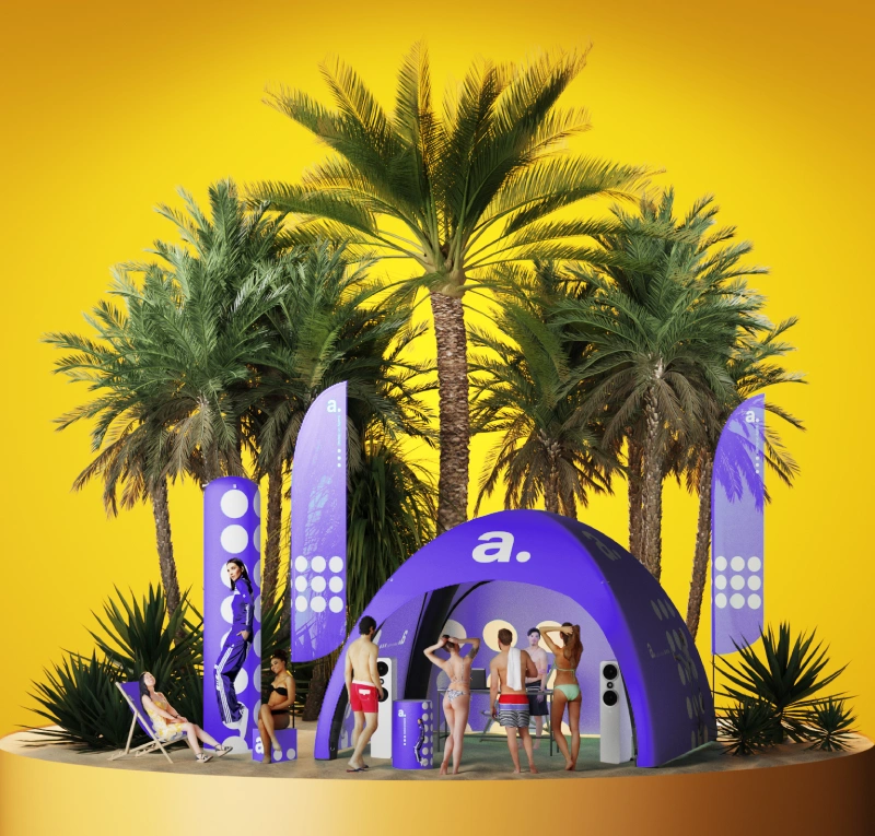 Strefa eventowa z flagami i namiotami reklamowym oraz plażowiczami na tle palm.