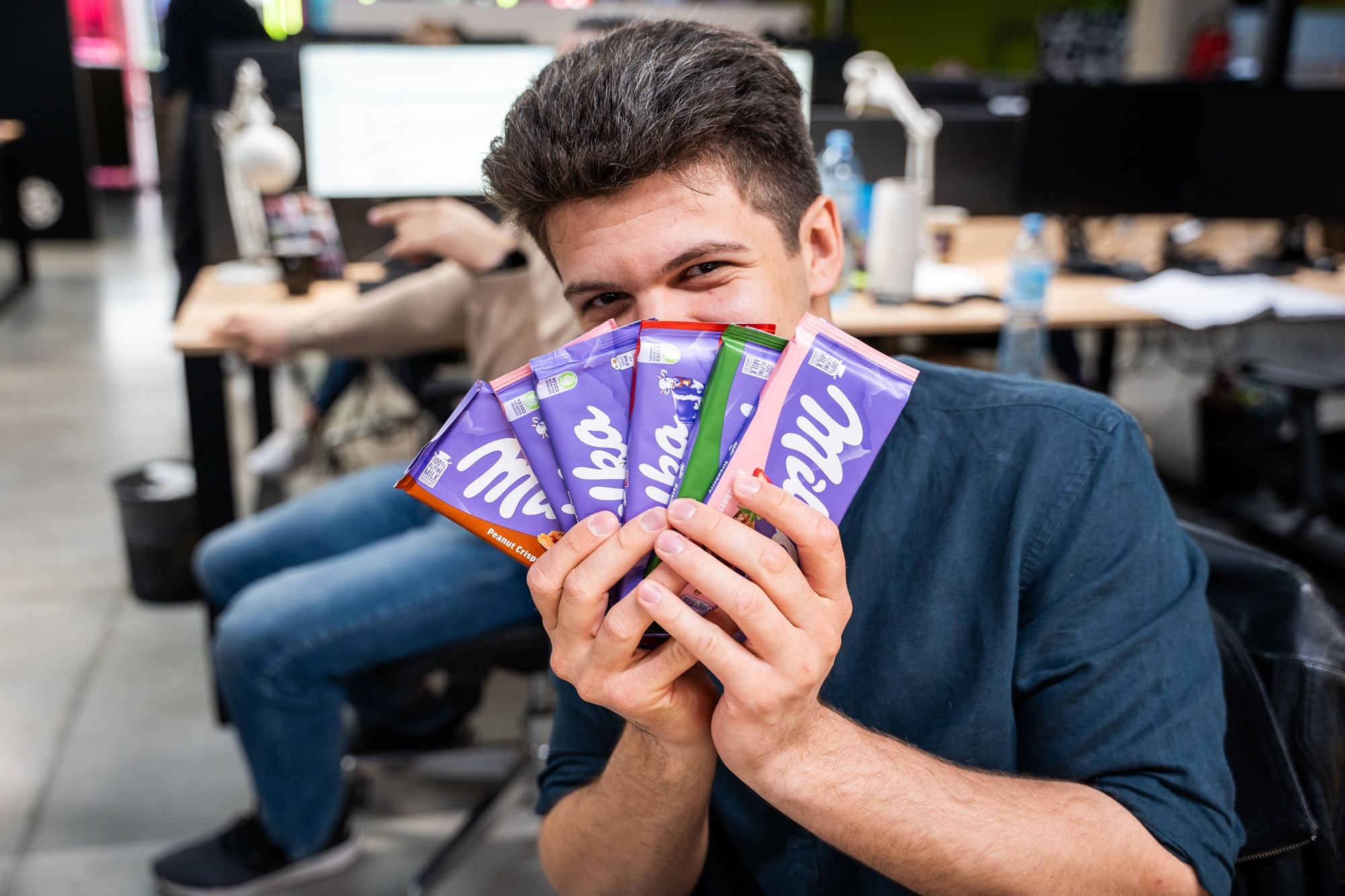 chłopak trzymający wachlarz z czekolad w ręce, zasłaniający nim swoją twarz