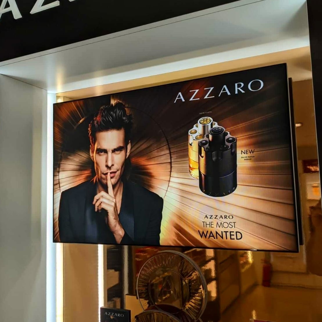 Podświetlany kaseton reklamowy perfum marki premium zawieszony w witrynie sklepowej