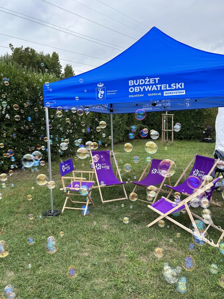 Namiot reklamowy, leżaki i pufy reklamowe, ustawione w ogrodzie podczas wydarzenia plenerowego