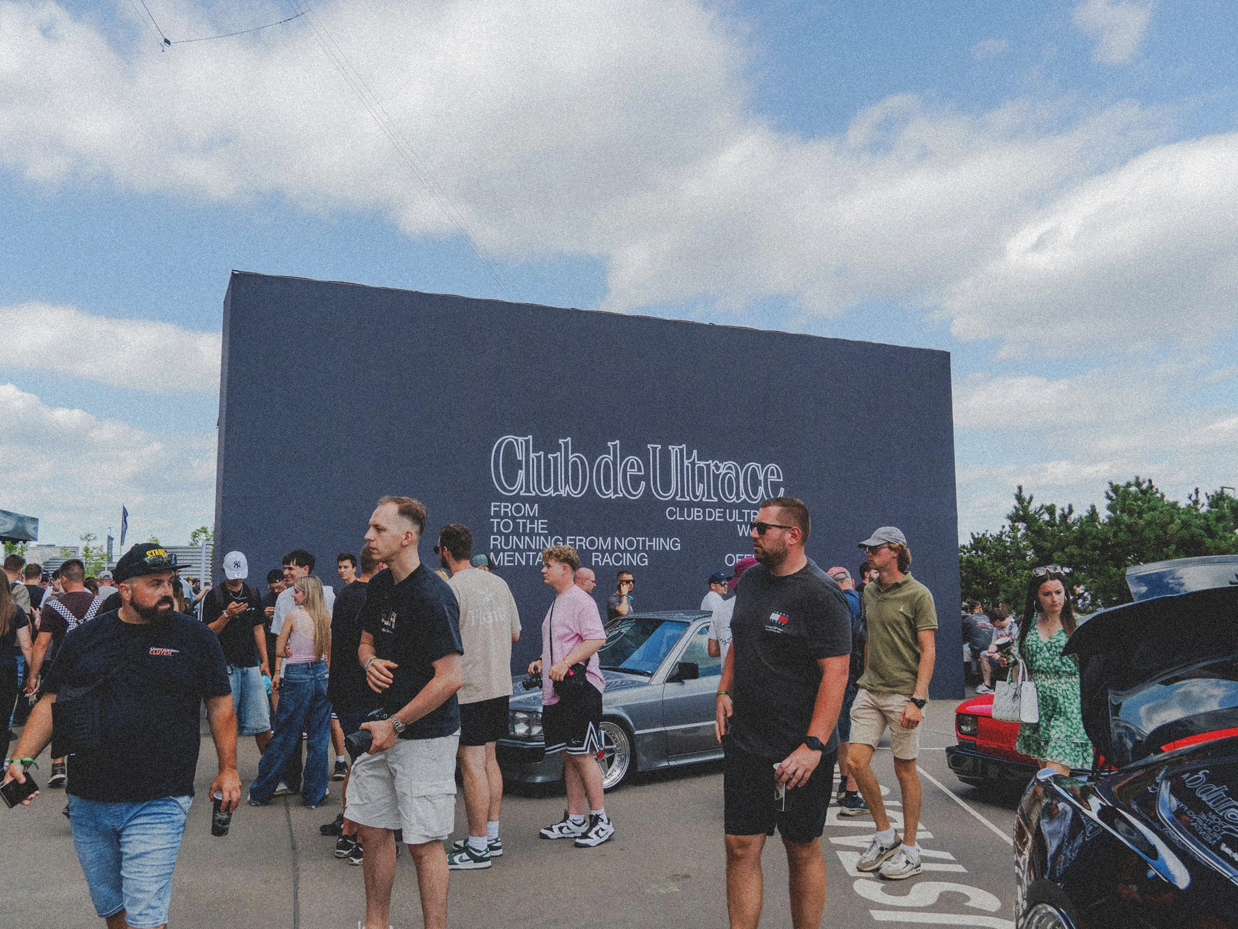 Tłum uczestników przechodzących obok ściany z napisem „Club de Ultrace” podczas wydarzenia Ultrace 2025.
